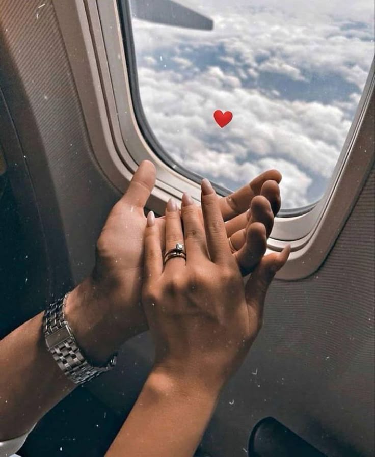 Couple holding hands by an aeroplane window